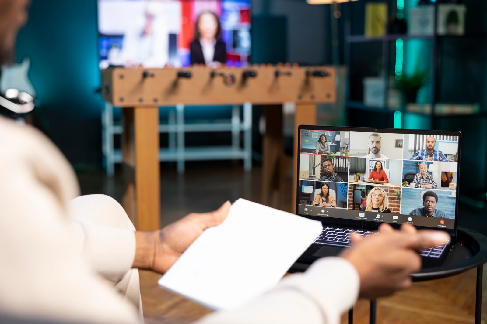 Management executive analyzing paperwork while holding videoconference meeting with remotely working multiethnic team. Manager teleworking in apartment, discussing project progress with workers